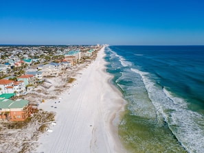 An aerial view of a beachside town with beachfront properties, a sandy beach, and ocean waves.