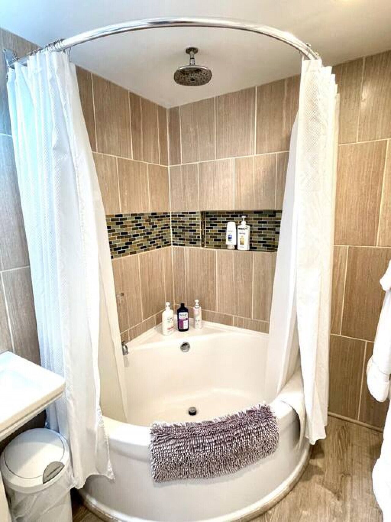 Een badkamer met een vrijstaand bad, douchegordijn en een betegelde douche.