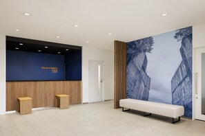 Un área de recepción con pared azul, paneles de madera, un banco y un mural grande en la pared.