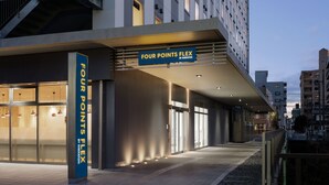Ein moderner Hotel Eingang, mit einem Schild, auf dem 'FOUR POINTS FLEX BY SHERATON' steht.