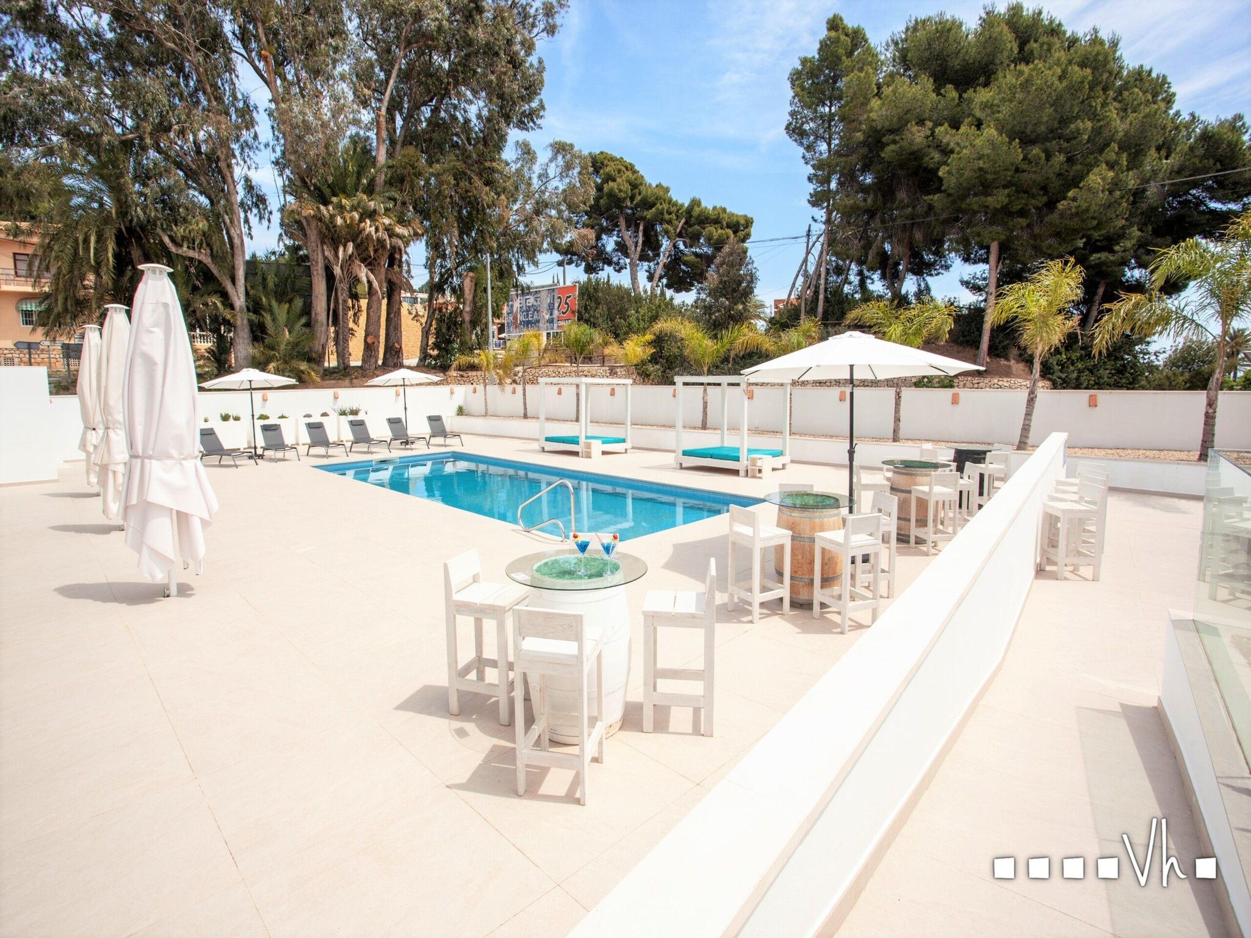 Un espace piscine aménagé sur le toit, avec des chaises longues, des parasols et un bar.