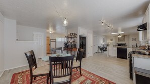 A spacious kitchen with modern appliances, a dining area with a wooden table and chairs, and a living area with a sofa and a coffee table. - NEW Renovated Private 3/2Home(King)Near Balloon Fiesta Park, Quiet Neighborhood! (Albuquerque)
