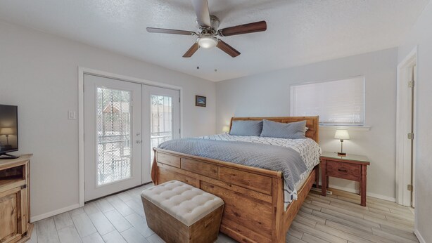 A bedroom with a wooden bed, a ceiling fan, a bench, a TV, and a window with blinds. - NEW Renovated Private 3/2Home(King)Near Balloon Fiesta Park, Quiet Neighborhood! (Albuquerque)