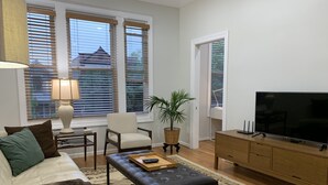 Una sala de estar con sofá, sillón, mesa de centro, televisor y una planta en maceta.