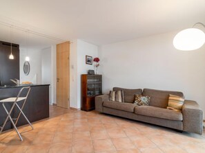A modern living room with a sofa, a coffee table, a cabinet, and a dining area with a chair.