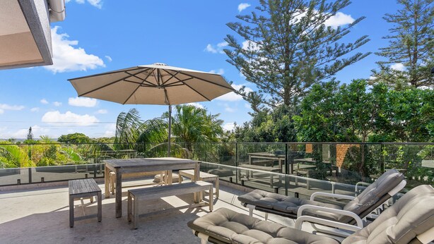 A rooftop patio with a table, chairs, and a lounge area with cushions. - Byron Breeze 7 ~ Luxury Penthouse 3 Bedroom Apartment (Byron Bay)