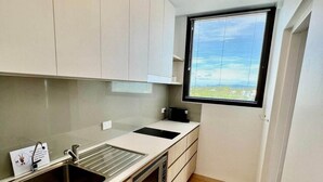A modern kitchen with a built-in oven, a sink, and a window with blinds. - It's all about the views! (Townsville City)