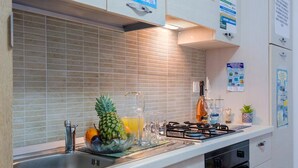 Una cocina moderna con salpicadero de azulejos, electrodomésticos de acero inoxidable y un bol de fruta en la encimera.