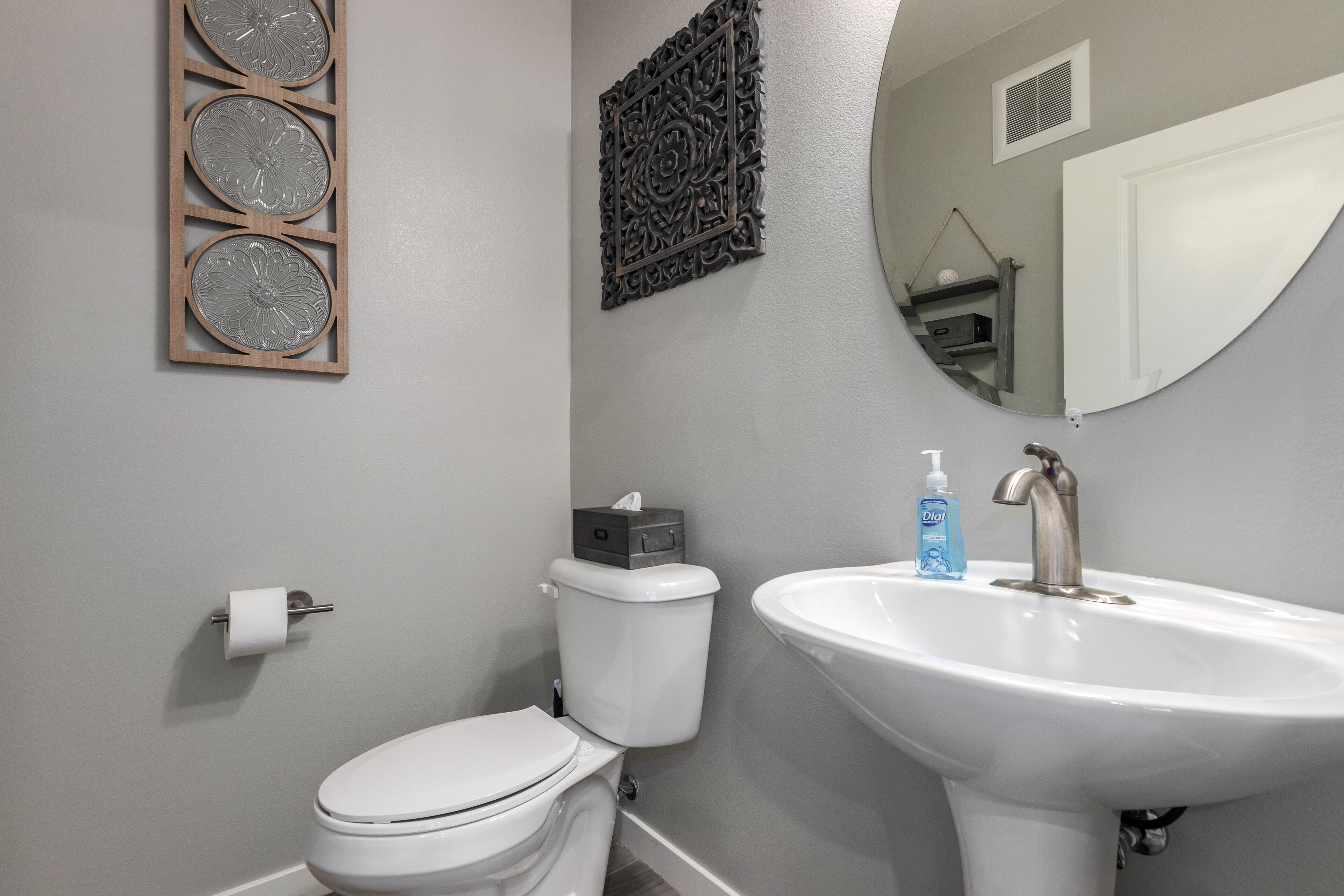Een badkamer met toilet, wastafel en decoratieve muurkunst.