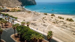 Eine Küstenstraße mit Strand, einem felsigen Felsen und Booten im Wasser.