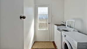 A laundry room with a door, a washing machine, and a dryer. - Bach on Pitau - Mt Maunganui Holiday Home (Mt Maunganui)