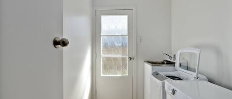 A laundry room with a door, a washing machine, and a dryer.