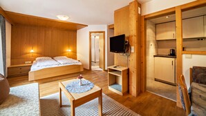 A bedroom with a bed, bedside tables, a TV, a small table with a vase, and a wooden wardrobe. - Vacation Apartment "Moosmair 2" with Mountain View, Wi-Fi, Balcony & Garden (St. Martin in Passeier)
