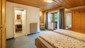Habitación con paneles de madera, una cama, baño y vistas a la vegetación.