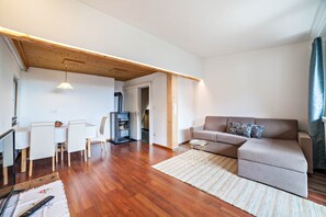A modern living room with a wooden ceiling, a sofa, a dining table with chairs, and a TV. - Apartment "Moosmair 4" with Mountain View, Fireplace, Wi-Fi, Balcony & Garden (St. Martin in Passeier)