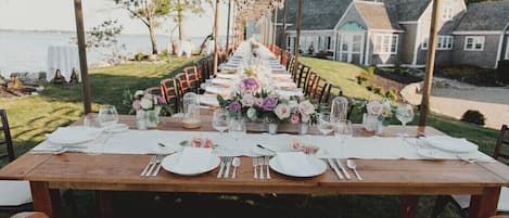 Enjoy a formal outdoor dining experience with a beautifully set table amidst a serene natural setting.