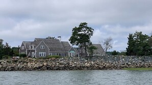 Une grande maison avec un mur en pierre et un arbre devant.