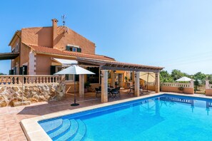 A poolside area with a pool, outdoor furniture, and a building with a tiled roof. - Villa Bonavista with Mountain View, Private Pool, Wi-Fi, Terrace & Garden (Capdepera)