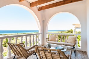A balcony with wicker furniture, a glass table, and a view of the sea. - Villa 4 Bedroom - Panoramic sea view - Heated pool (San Jaime)