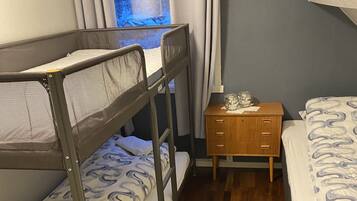 A bunk bed room with a wooden nightstand and a window with curtains.