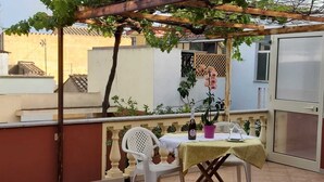Un patio con mesa y sillas, una pérgola y una planta en maceta.
