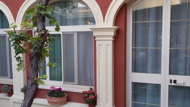 Un edificio con ventanas de arco y una enredadera trepando por la pared.