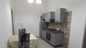 Una cocina compacta con una mesa y sillas, estufa y horno empotrado.