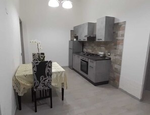 Een koelkast, een oven, een kookplaat, kookgerei, borden en bestek