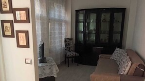 Una sala de estar con un sofá, un aparador y cuadros en la pared.
