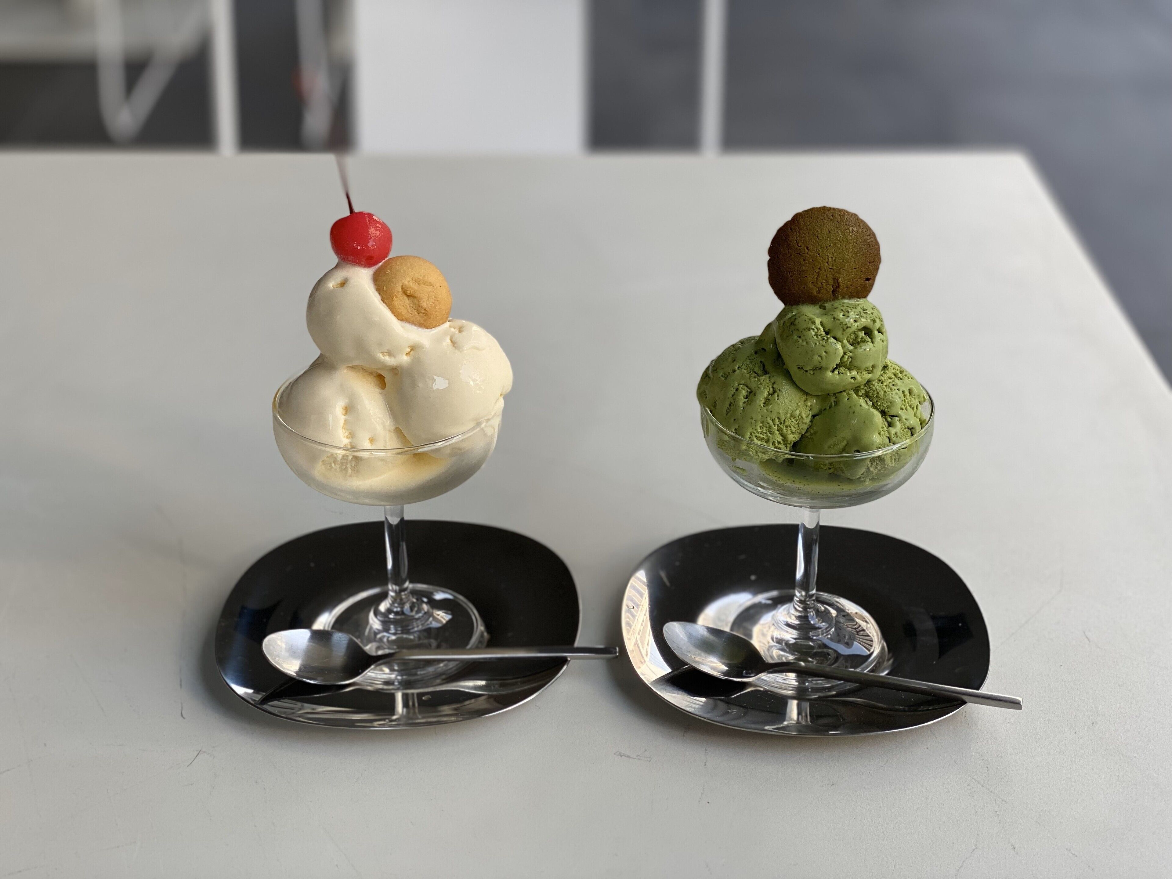 Two dessert cups on a table with spoons.