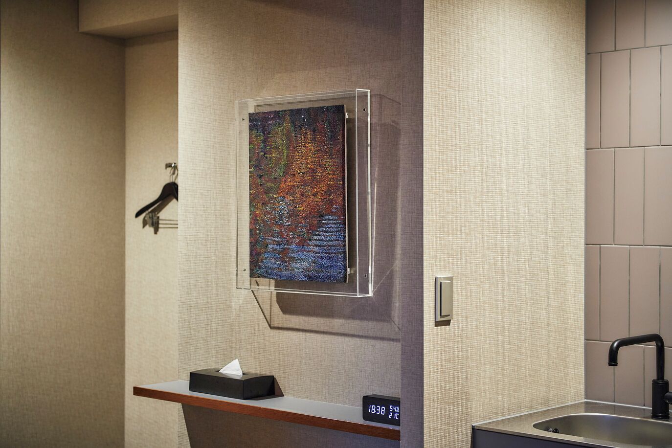 A bathroom with a sink, a mirror, a towel rack, and a wall-mounted painting.