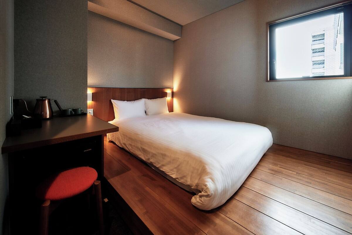 A hotel room with a bed, a desk, and a chair.