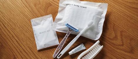 A wooden surface with a beauty set bag, a stretch body towel, a toothbrush, a tube of toothpaste, and a comb.