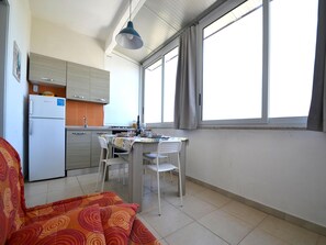 A compact kitchen with a dining area, a sofa, and a window providing natural light.