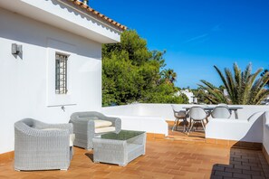 A terrace with wicker furniture, a table, and chairs.