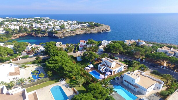 A coastal residential area with houses, a swimming pool, and a view of the sea. - Villa "Luna" with Sea Views, Pool, Air Conditioning, Terraces & Garden (Cala d'Or)