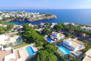 A coastal residential area with houses, a swimming pool, and a view of the sea.