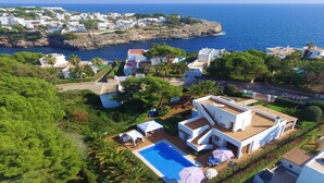 A coastal villa with a swimming pool, white architecture, and lush greenery. - Villa "Luna" with Sea Views, Pool, Air Conditioning, Terraces & Garden (Cala d'Or)