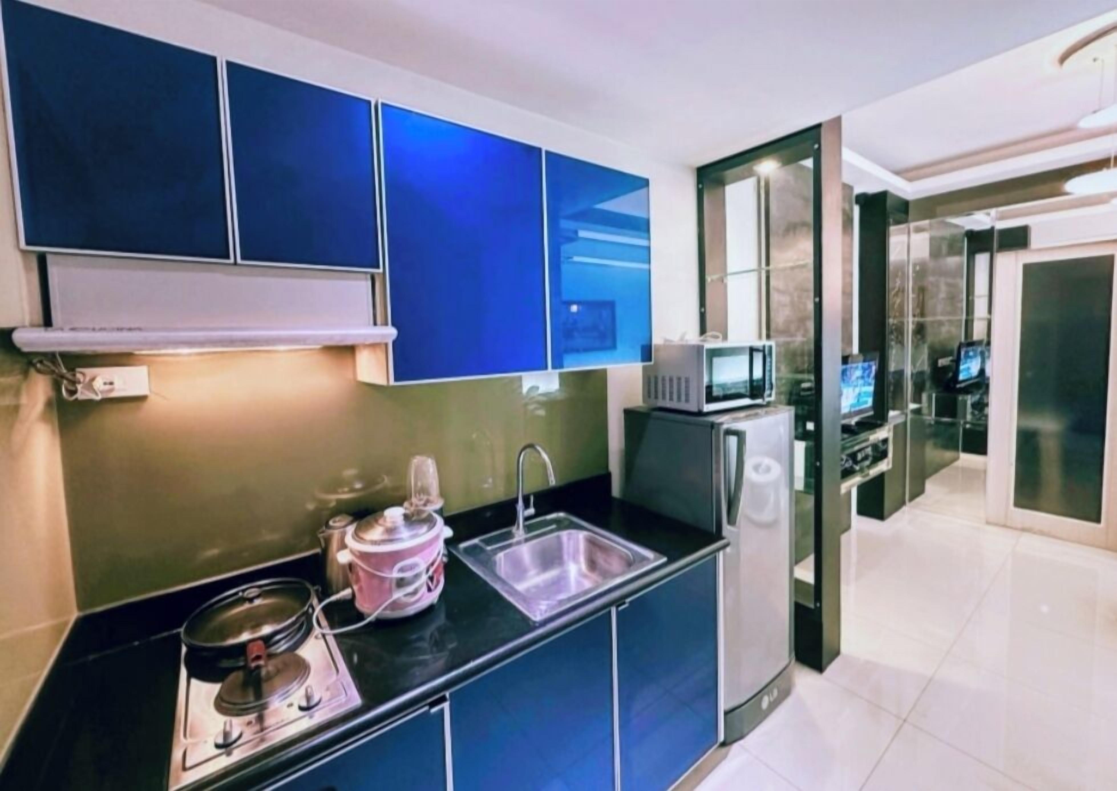 A modern kitchen with a black countertop, stainless steel appliances, and blue cabinets.