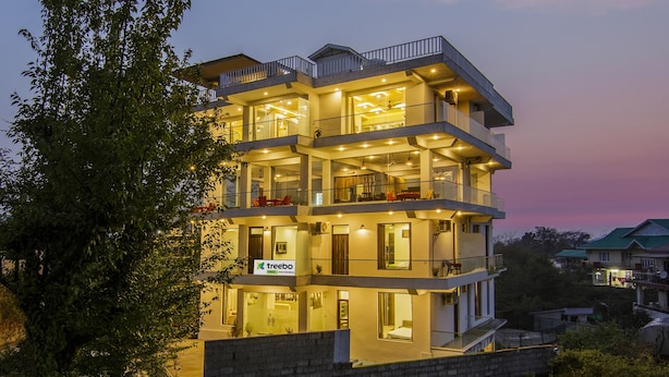 Un hôtel à plusieurs étages doté de balcons, de grandes fenêtres et d’une enseigne indiquant qu’il s’agit d’un établissement de la chaîne Treebo Trend.