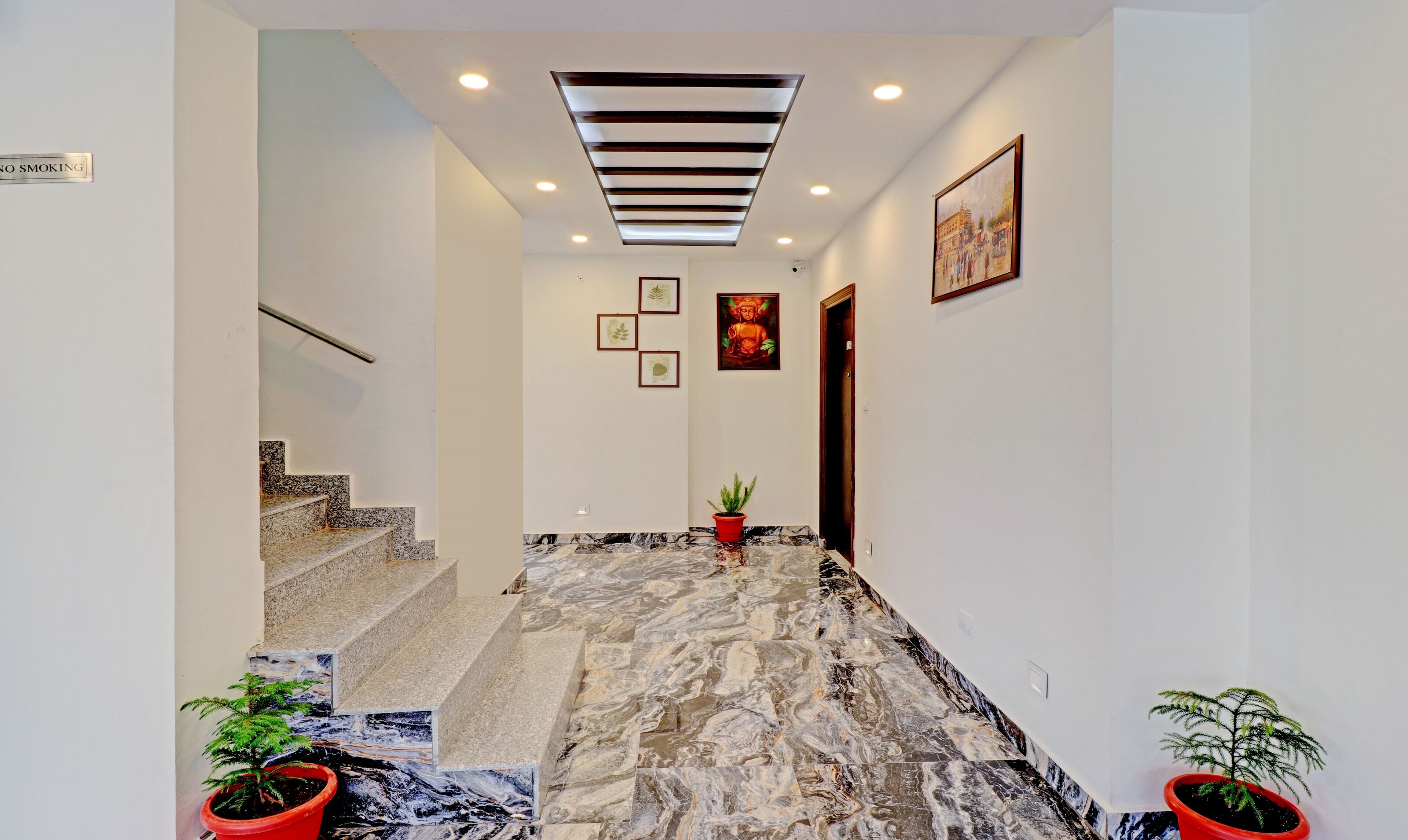 A hallway with marble flooring, a staircase, and a ceiling light fixture.