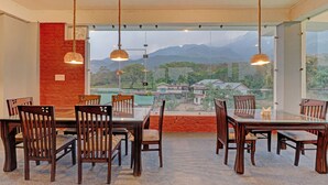 Un coin repas avec une table et des chaises en verre, un mur en briques et une vue sur des maisons et des montagnes.