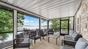 A modern outdoor seating area with a view of a lake and trees.