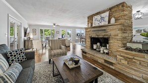 A spacious living room with a stone fireplace, a sofa, a coffee table, and a view of the outdoors.