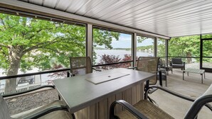 A conference room with a table and chairs, large windows offering a view of a lake and trees.