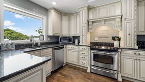 A kitchen with white cabinetry, a stainless steel dishwasher, a double oven, and a microwave.