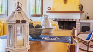 A wooden table with a bowl of decorative items, a lantern, and a placemat with a logo. - Vacation Home Es Garballons with Garden, Wi-Fi, Pool & Terrace (Manacor)