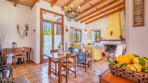 A dining area with wooden furniture, a chandelier, and a fireplace. - Vacation Home Es Garballons with Garden, Wi-Fi, Pool & Terrace (Manacor)
