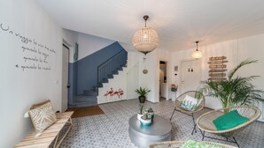 Un interior moderno con una escalera, muebles de mimbre, una lámpara decorativa en el techo y una pared con señalización.