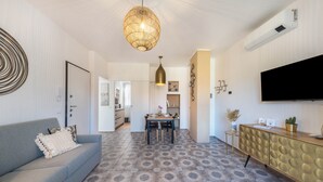 Una sala de estar moderna con un sofá, una mesa de comedor y un televisor montado en la pared.